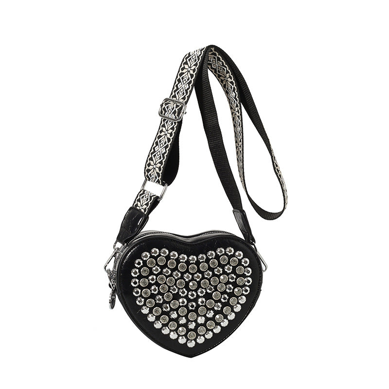Hjerteformet taske med bred skulderrem i westernstil, der matcher nitter og som crossbody-telefontaske